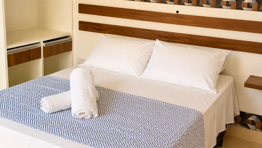 Detalhe da cama com enxoval e toalhas