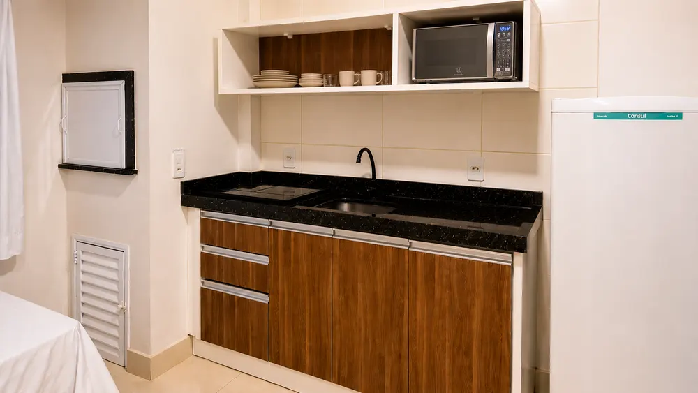 Cozinha equipada com bancada, pia, micro-ondas e armários